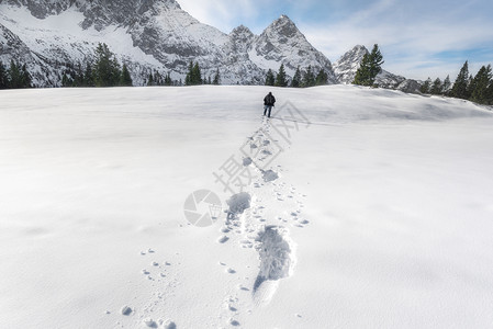 人走过雪层向山峰和林脚步在雪中冬季风景图片