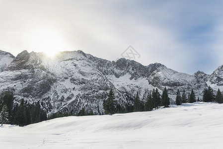 太阳升起照在白雪皑皑的山脉上图片