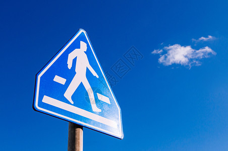 蓝色横行人交叉标志对着蓝天一边有复制空间图片