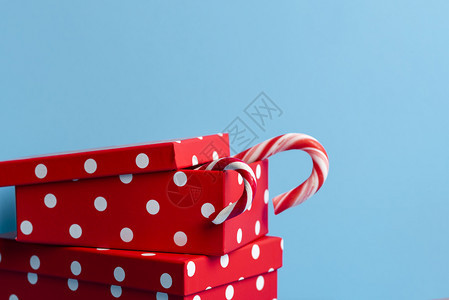 红色礼物盒上面有白色斑点和糖果甘蔗蓝色背景圣诞节礼物xmas红礼物概念冬季假日传统图片