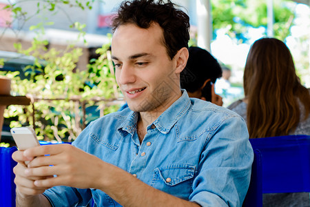 年轻人坐在咖啡店里使用智能手机图片