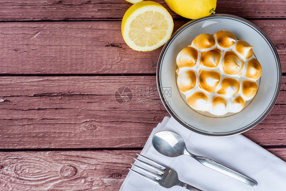 新鲜自制柠檬派配有蛋白糖和木制桌上的柠檬柑橘水果图片