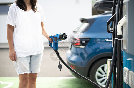 妇女收费电动汽车充电电源插座绿色生态概念图片