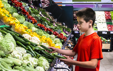 儿童在超市的货架上选择蔬菜图片