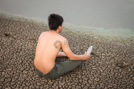 水危机人坐在裂开的地上接近干燥的水图片