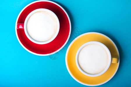 美丽的咖啡黄色和红杯子蓝背景加卡布奇诺图片