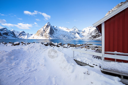 传统的挪威木制屋在峡湾的岸边和远处山上站立高清图片