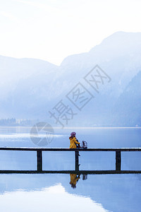一大早带着背包坐在山湖上的木桥美丽的风景和反光图片
