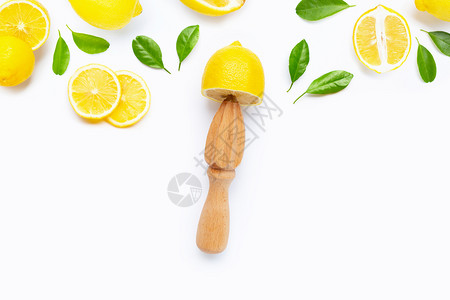 白色背景上带木制果汁机的新鲜柠檬和叶子复制空间图片