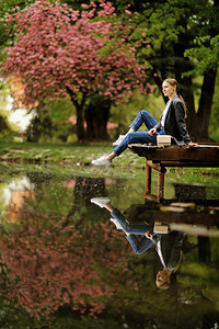 在湖边的木桥上漂亮女孩在阳光明媚的一天在湖边木桥附近美丽的女人肖像一个孤独女孩在大气中行走的肖像在阳光明媚的一天在湖边木桥上美丽图片