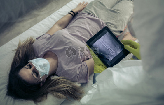 生病的妇女躺在一个医院的担架上有细菌防护服的人理生病的妇女躺在医院担架上图片