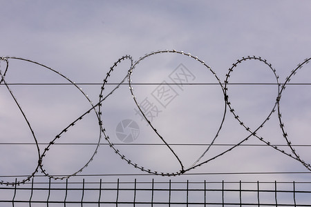 铁丝网从监狱栅栏上刺铁丝网被囚禁奴役犯被定罪监禁检查站安全区边境军事基地的概念图片