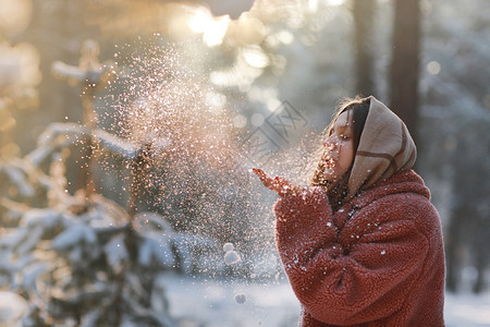 美丽的时尚年轻女孩在冬天森林中吹雪圣诞节的假期美丽在冬天森林中吹雪图片
