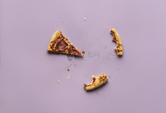 食用比萨饼概念仅用一片沙拉米披萨和紫色背景的结壳剩菜上面是被吞食的意大利披萨辣椒图片