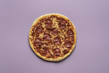 紫色背景的热辣椒尼比萨饼上面是意大利比萨饼和面板上的意大利辣椒和图片