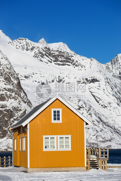 传统的挪威木制屋在峡湾的岸边和远处山上站立图片