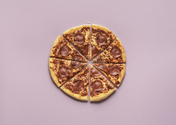 紫色背景的辣椒尼披萨切片在意大利披萨肉酱被切掉的部分上传统的意大利餐热辣的比萨饼图片