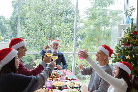 欢呼老人戴红帽子在圣诞节日与家人共进晚餐图片
