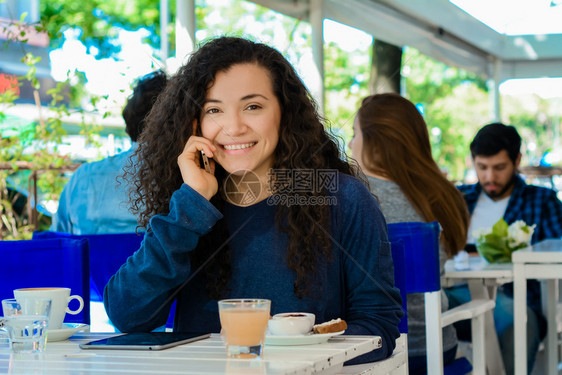 美丽的年轻拉丁女人肖像在咖啡店的手机上聊天图片