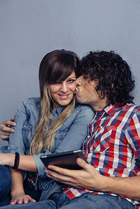 爱与休闲时间概念男人亲吻年轻女子并持有平板电脑图片