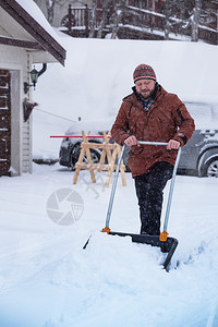 冬天在院子里铲雪的中年男性图片