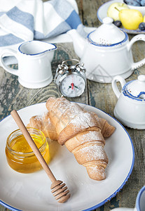 一份小早餐由杯茶和份蜂蜜的羊角面包组成图片