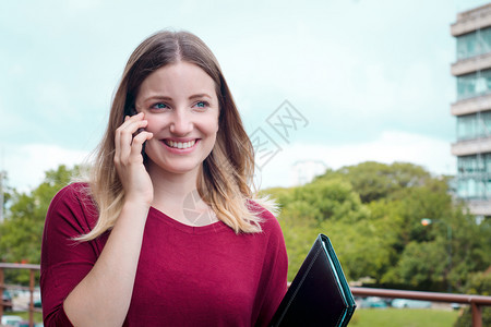 年轻美女在户外用手机聊天的肖像图片