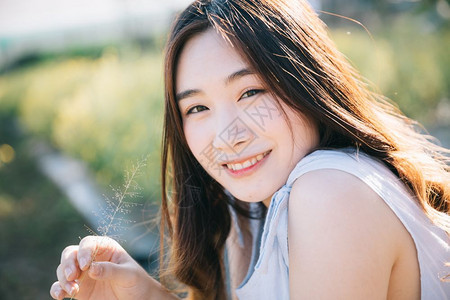 坐在花园里微笑着的年轻亚洲女孩肖像图片