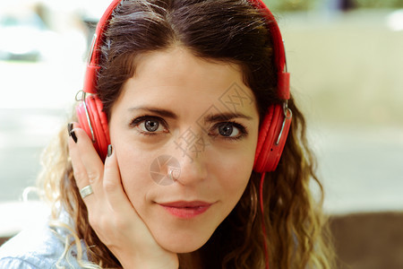 快乐的年轻女子在街上用耳机听音乐夏季生活方式图片