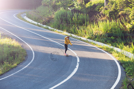 女孩骑滑板在阿尔卑斯山的公路上图片