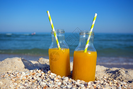 两瓶橙汁加稻草在海洋上暑假图片