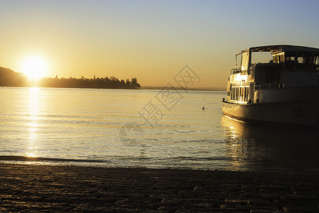 日出在水面上船康斯坦湖上在德国的康斯坦河预示着湖岸和一艘朝日出方向航行的船水上航行图片