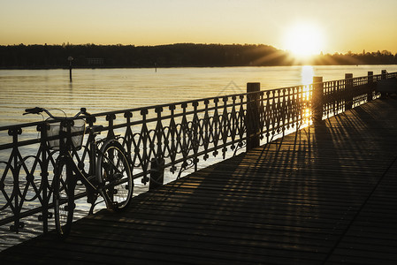 日出时在康斯坦兹德克萨州康坦兹湖边的一座木制码头上废弃了自行车黎明时分甲板在波德西湖上空边阳光明媚的一天图片