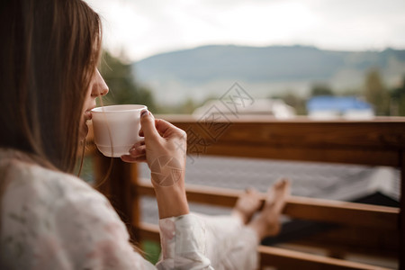 在阳台上喝咖啡欣赏美景的女士图片