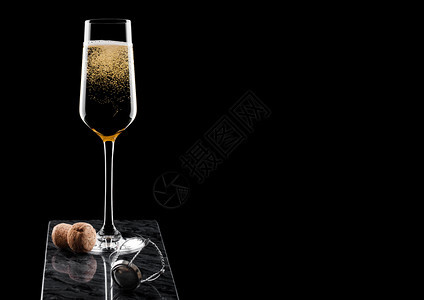 优雅的黄色香槟杯子黑大理石板上的软木和铁丝笼图片