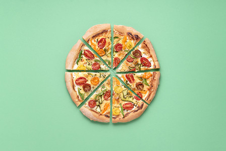 整个披萨初生在绿色背景上切成一片的在素食披萨上意大利菜披萨和樱桃西红柿土制食物图片