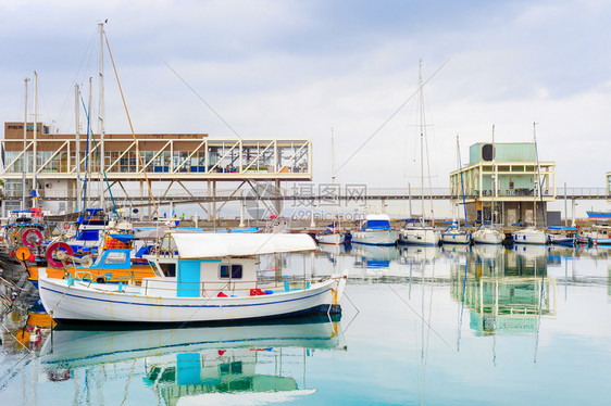 里马索市港景停泊的渔船在重天空下码头的餐馆和雨云辛普勒图片