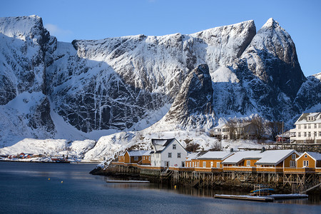 传统的挪威木制屋站在峡湾的岸边和远处山上岛屿北部图片