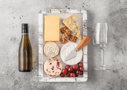 白葡萄酒和在木箱中挑选各种奶酪和木底葡萄图片