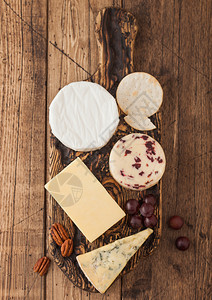 板上各种奶酪的选择木制背景蓝色的stilon红色的李斯特旧式切削板上的小奶酪图片
