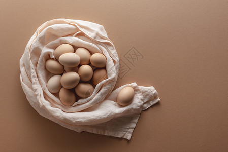 厨房毛巾巢里的新鲜鸡蛋堆放在棕色纸面背景上高于有机鸡蛋的视野褐色鸡蛋堆是东方的土质未烹煮的鸡蛋图片