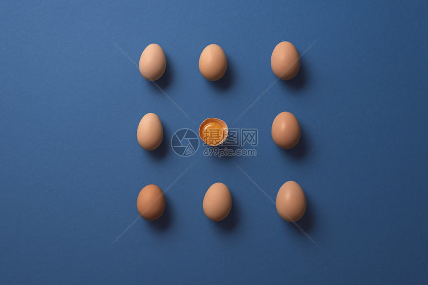 一个蛋和配对在蓝纸背景上平整的有机鸡蛋对称半个蛋和许多全图片