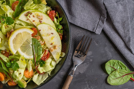 新鲜蔬菜沙拉加番茄苹果坚种子和柠檬橄榄油倒入沙拉碗图片