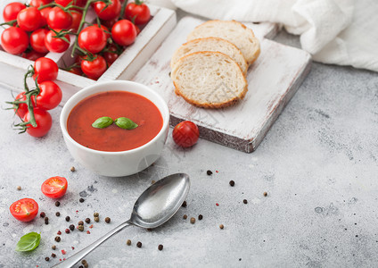 白碗盘的奶油番茄汤匙在浅底背景上还有一盒生番茄和面包文本空间图片