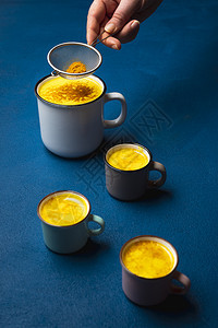 在典型的蓝桌上妇女准备调味拿铁饮料喝黄牛奶脱毒调味饮料图片