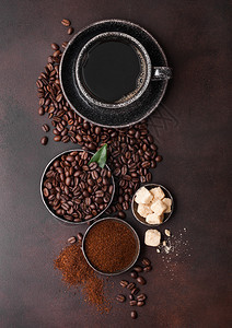 含有豆子和甘蔗糖块的土粉和深底咖啡树叶的黑陶瓷杯图片