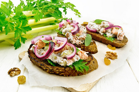 鲑鱼茶菜葡萄干胡桃红洋葱和加烤面包的奶酪沙拉木板上纸面的绿色生菜图片
