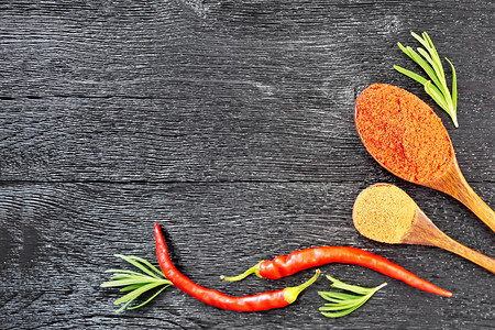 新鲜迷迭香红辣椒和两勺子木板上涂有土辣椒的鲜玫瑰红辣椒和两勺子架背景于上述木板图片