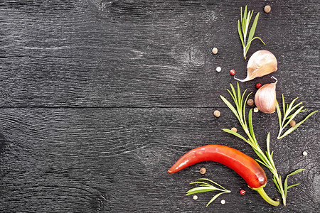 黑胡椒新迷迭香红辣椒和两片大蒜的豆子架在黑木板顶上图片