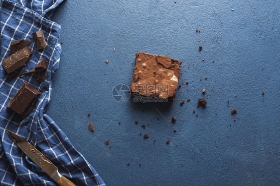 蓝桌上最后一块巧克力蛋糕上面有包屑餐巾纸和巧克力块上面有一个巧克力蛋糕方块吃了巧克力甜点图片